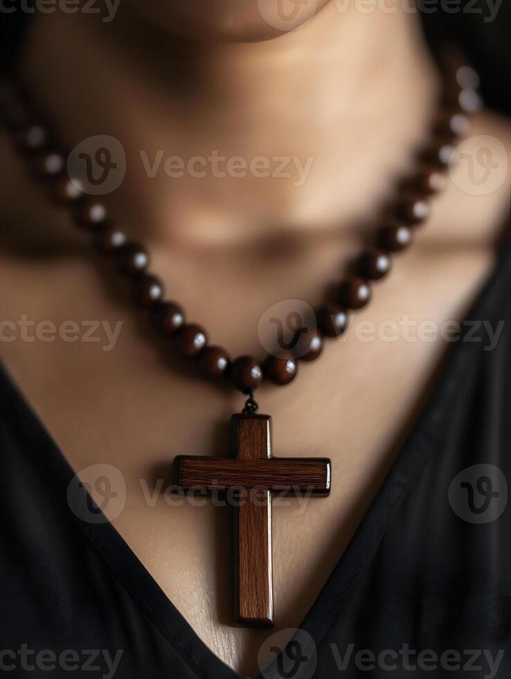 Person praying with a wooden rosary and crucifix to express faith and devotion photo