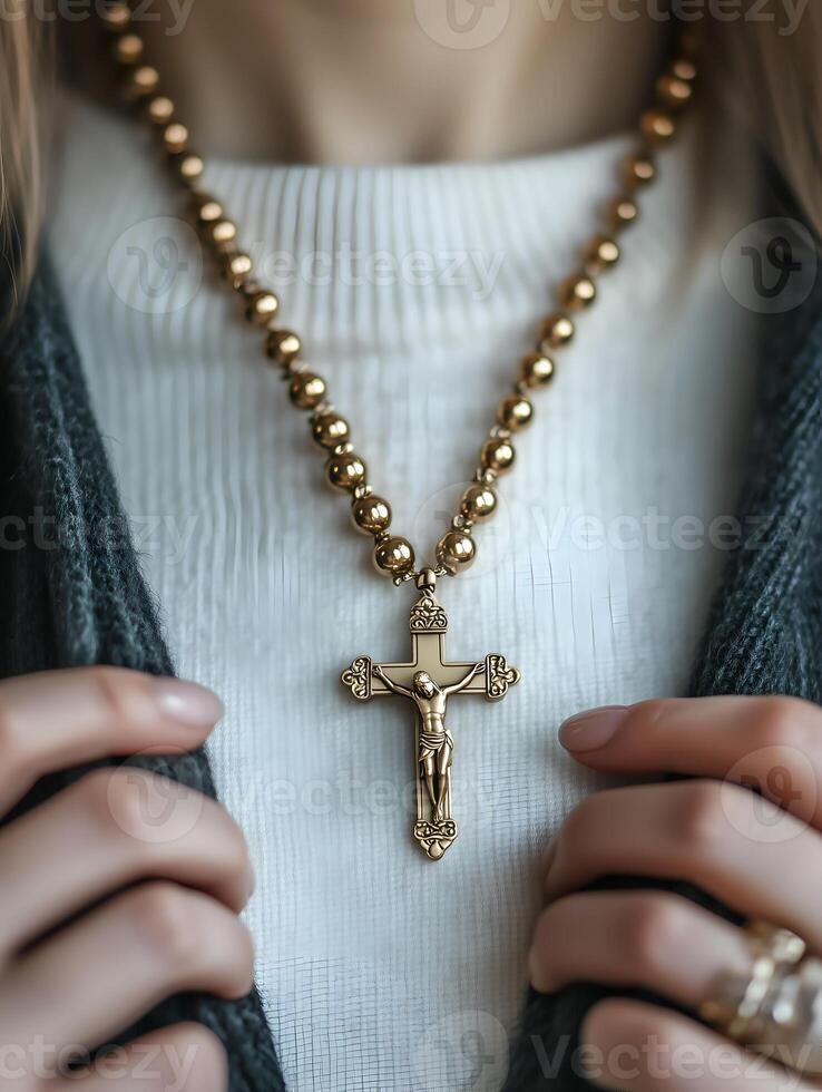 A person holds a golden rosary with a crucifix, engaging in prayerful devotion indoors photo