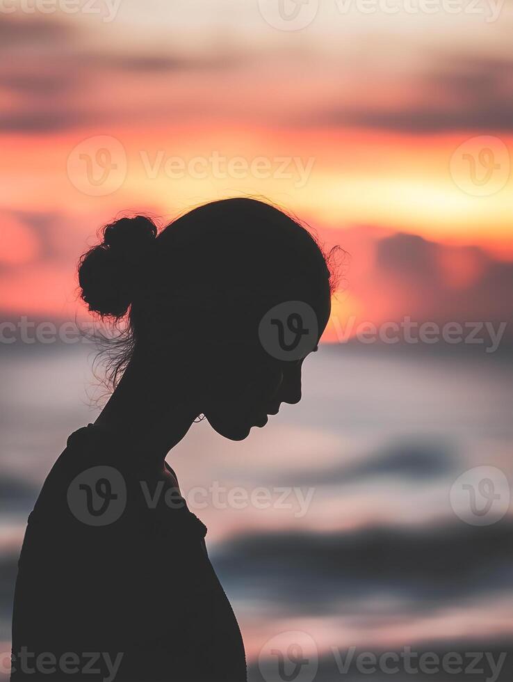 Silhouette of a person praying at sunset by the ocean, reflecting tranquility and connection photo