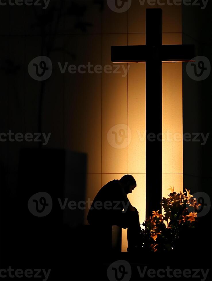 A priest in deep prayer before a cross illuminated at night in a peaceful location photo