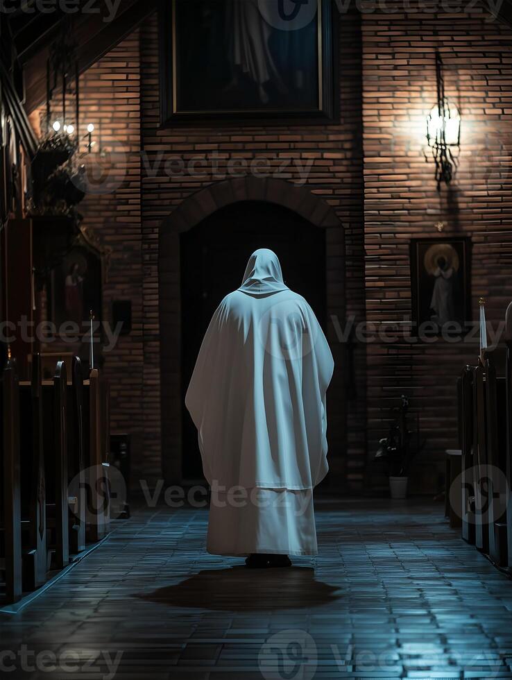 A priest prays quietly in a dimly lit church during a serene evening service photo
