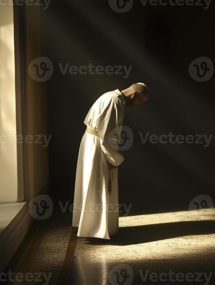 A priest in prayer kneels in a softly lit sanctuary, practicing reflection and devotion photo