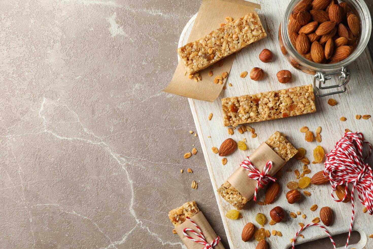 Board with tasty granola bars and nuts on gray background, top view photo
