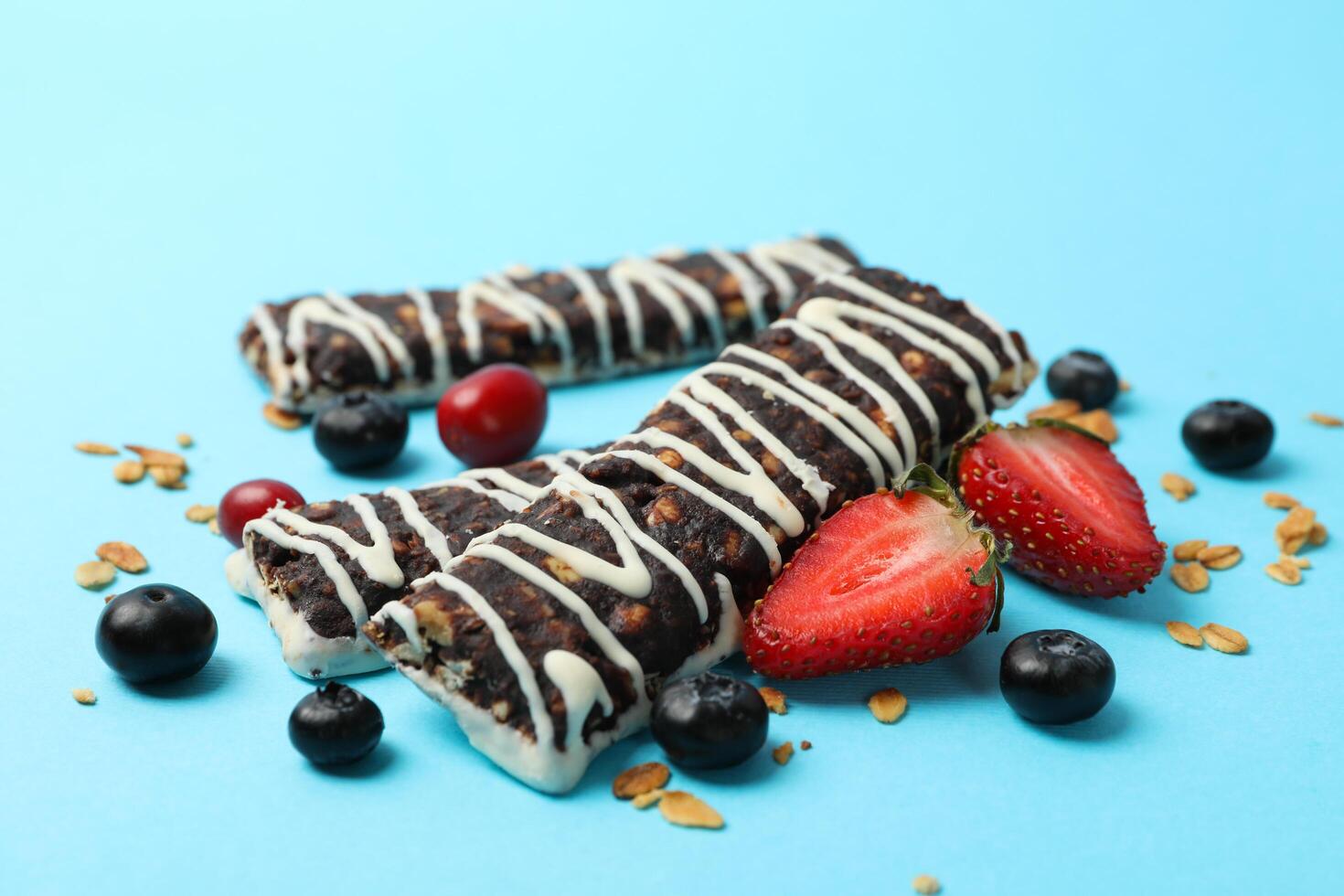 Tasty granola bars on blue background, close up photo