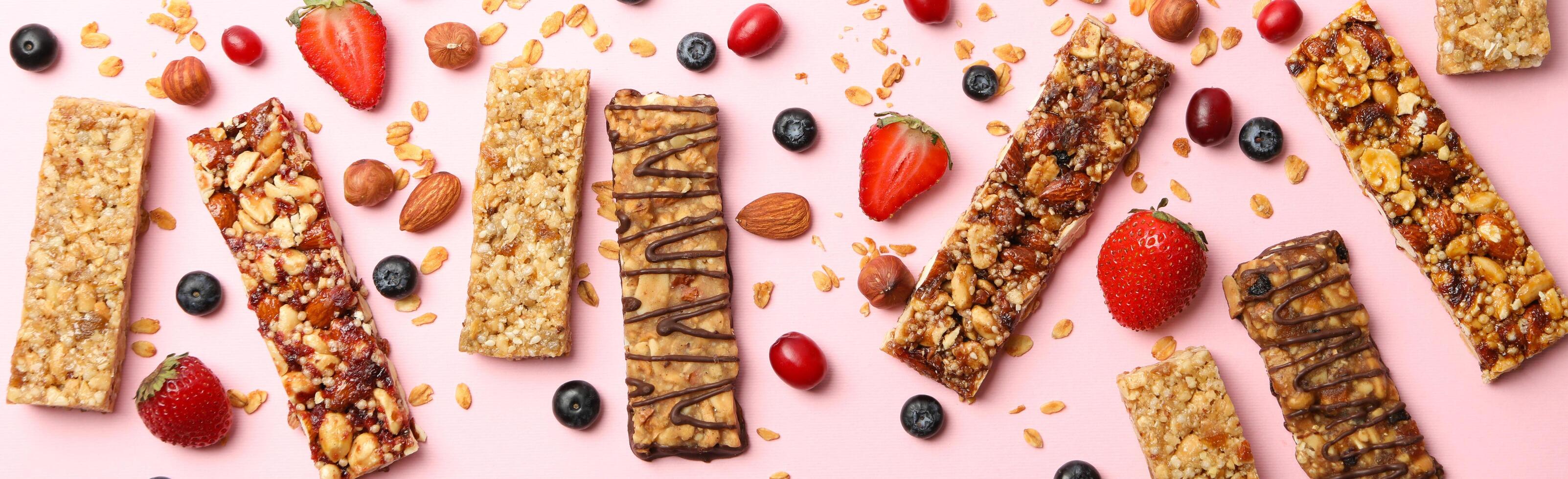 Tasty granola bars on pink background, top view photo