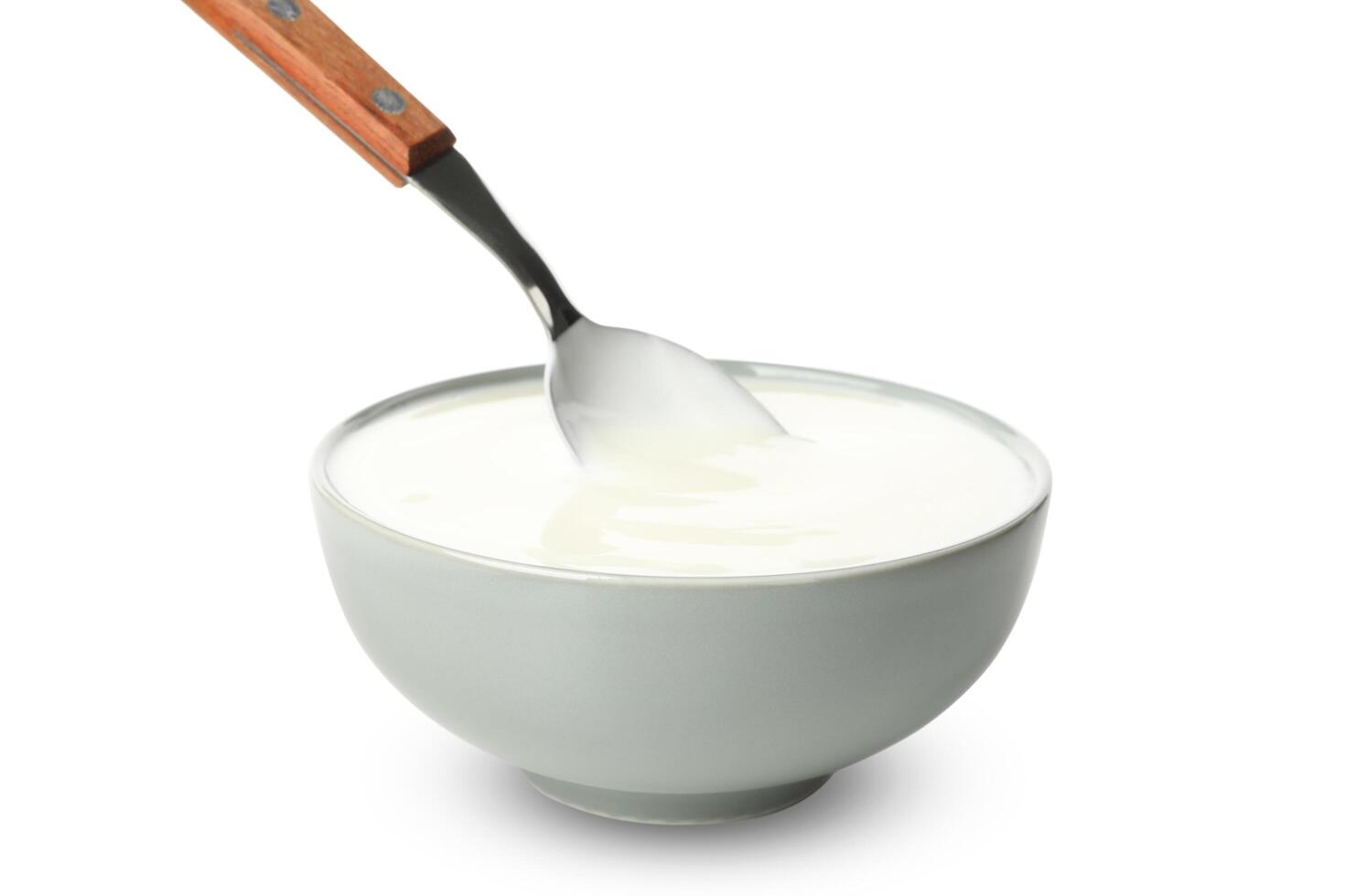 Bowl of sour cream yogurt and spoon isolated on white background photo