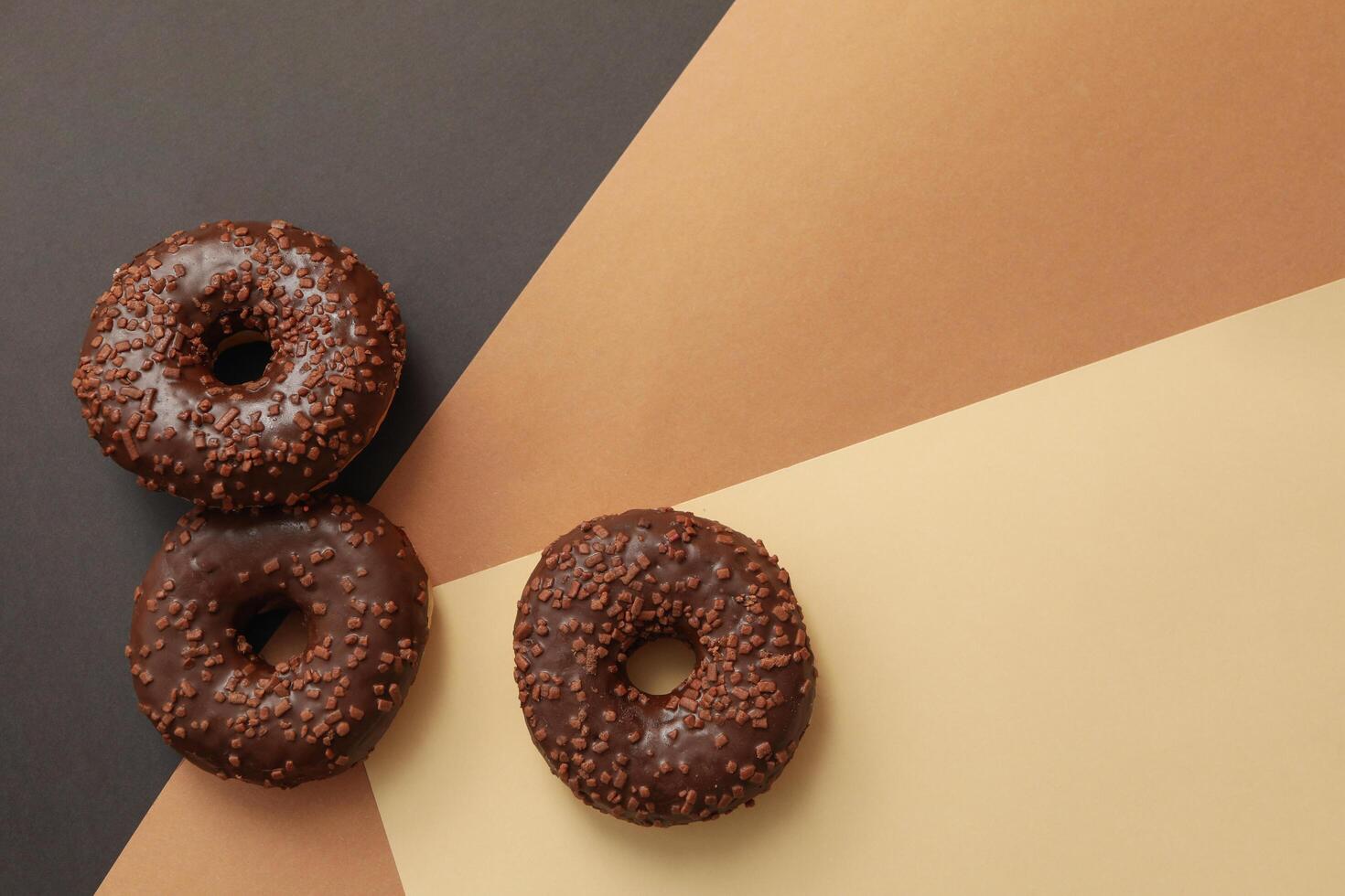 Tasty chocolate donuts on three tone background photo