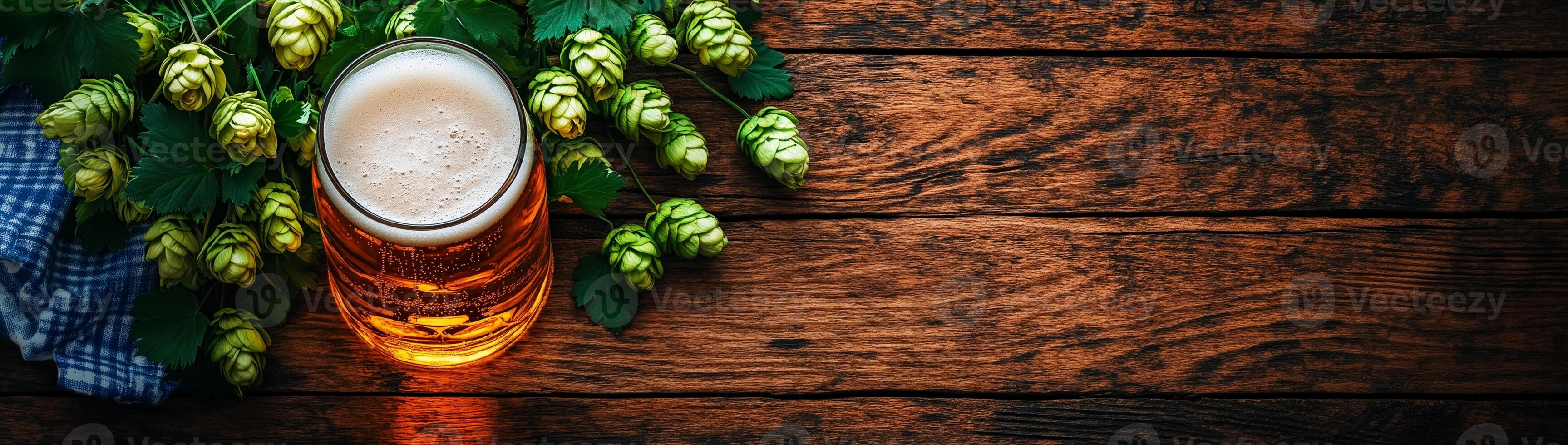 Glass of beer, green hops and checkered plaid on wooden background with space for text photo
