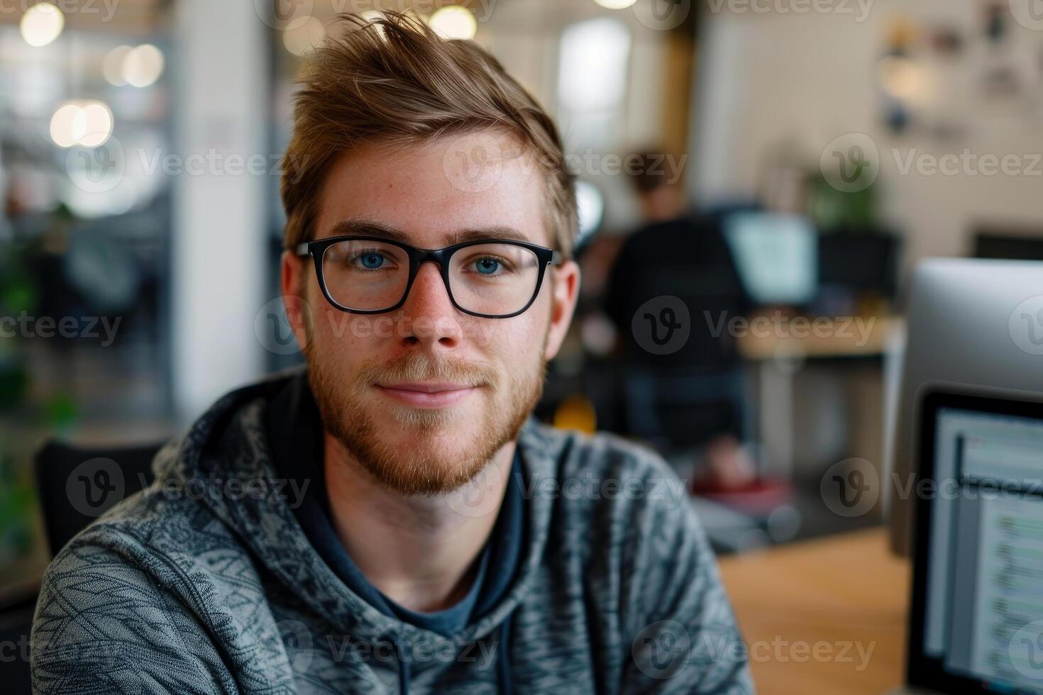Young professional smiling in busy open plan office photo
