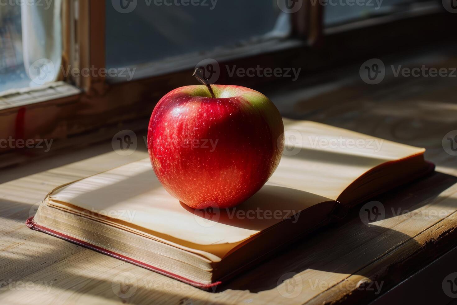 Red apple resting on open book by sunny window photo