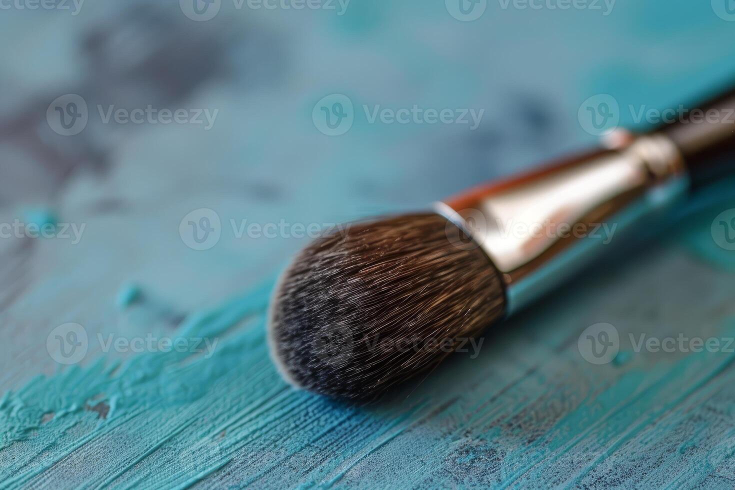 Makeup brush lying on a textured blue surface photo