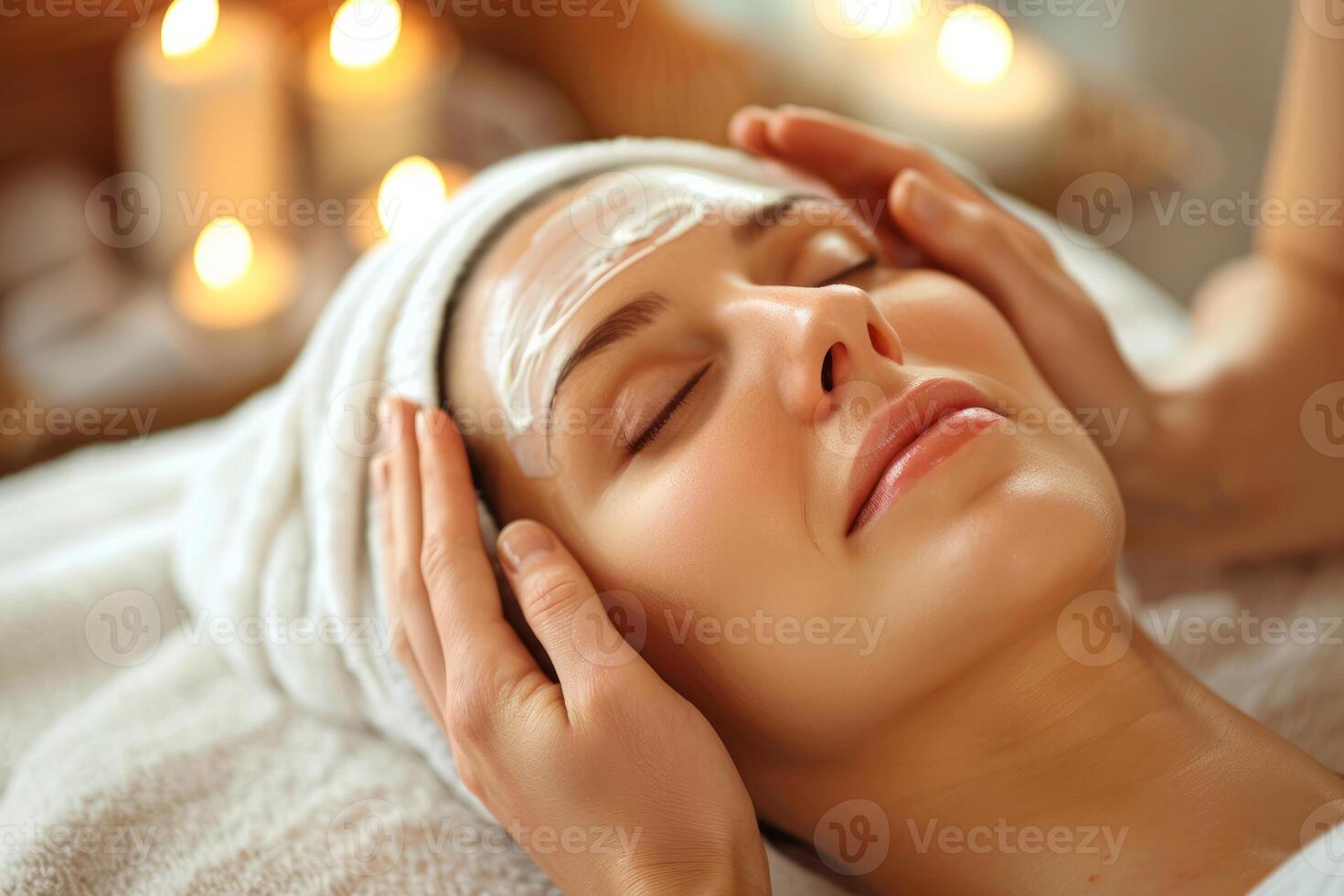 Beautician applying face mask to woman relaxing in spa photo
