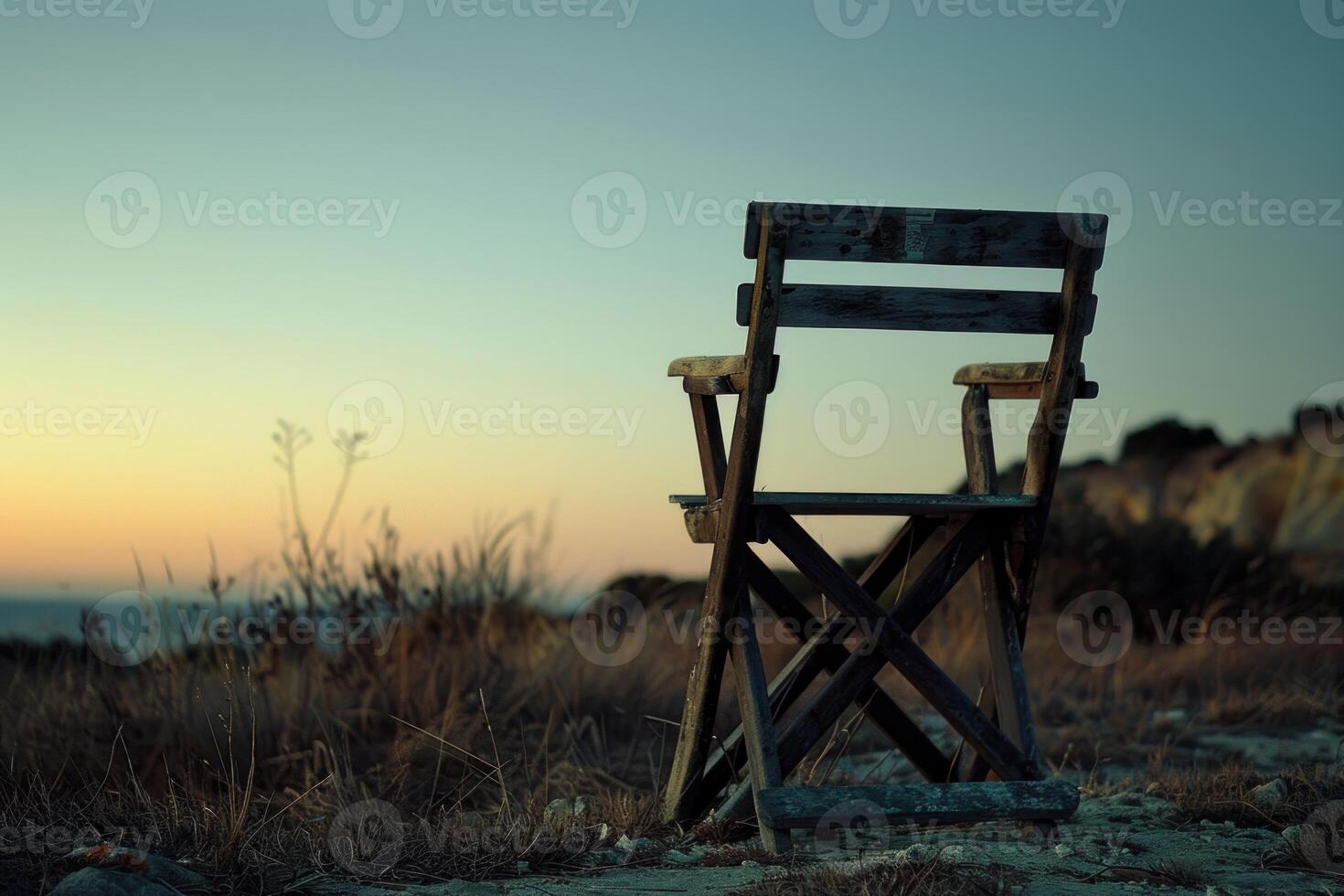 Old wooden chair standing on a cliff at sunset overlooking the sea photo