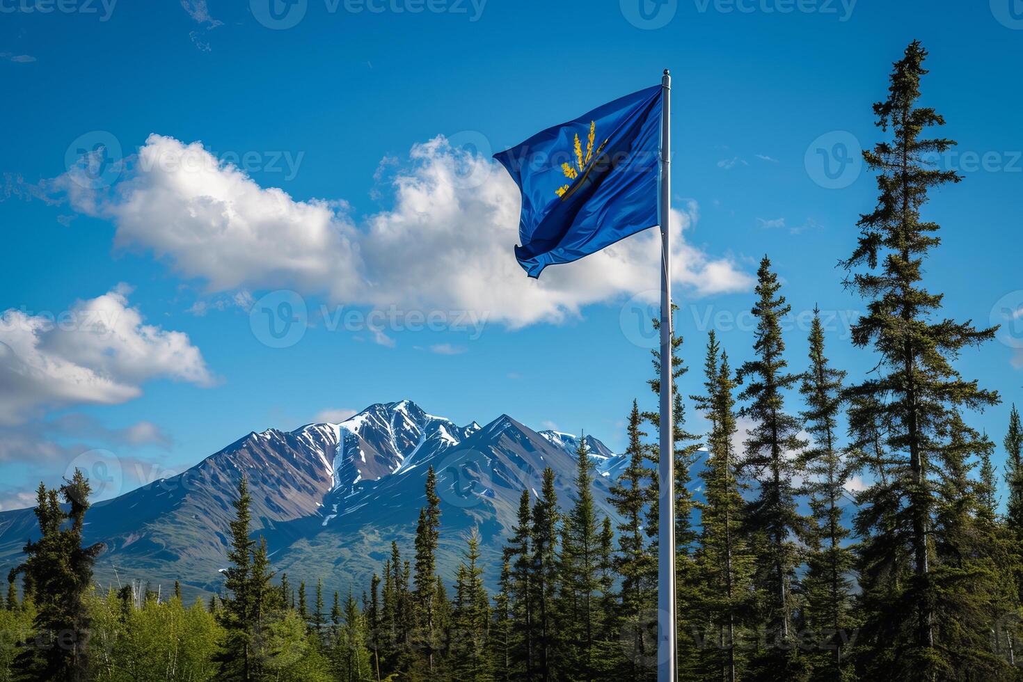 Alaskan flag waving in the wind with snow capped mountains and forest photo
