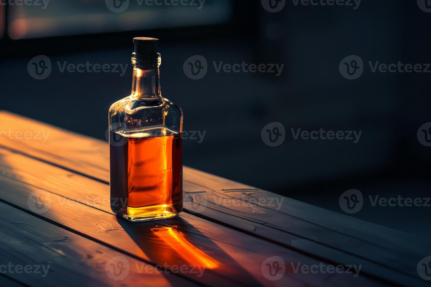Bottle of liquor casting long shadow on wooden table at sunset photo
