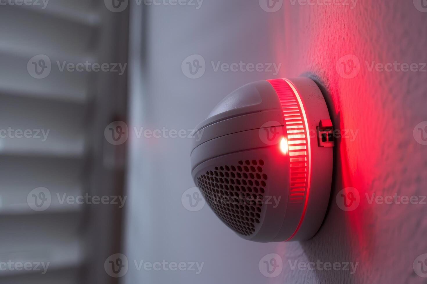 Modern smoke detector sounding an alarm on a white wall photo