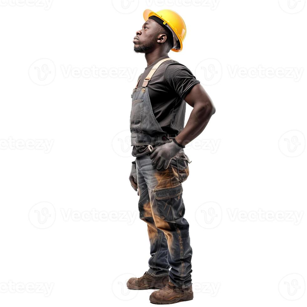 Construction worker wearing dirty overalls and yellow hard hat looking up photo
