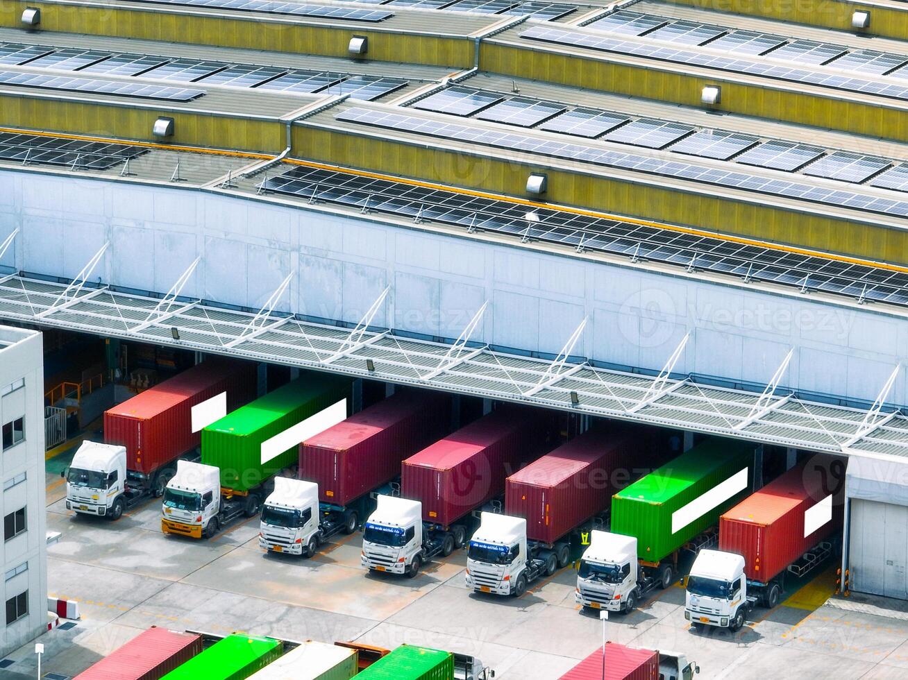 Solar-powered warehouse facility with freight trucks at loading docks. Eco-friendly logistics and efficient cargo transportation. Solar panels and sustainable energy concept in distribution center. photo