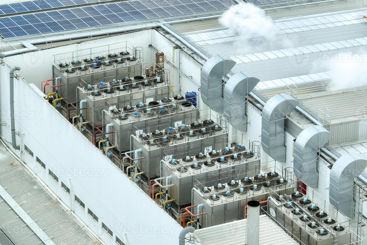 Sustainable industrial rooftop. Aerial view showcasing solar panels, ventilation systems, and industrial chillers. Renewable energy and efficient cooling in modern manufacturing facilities. photo