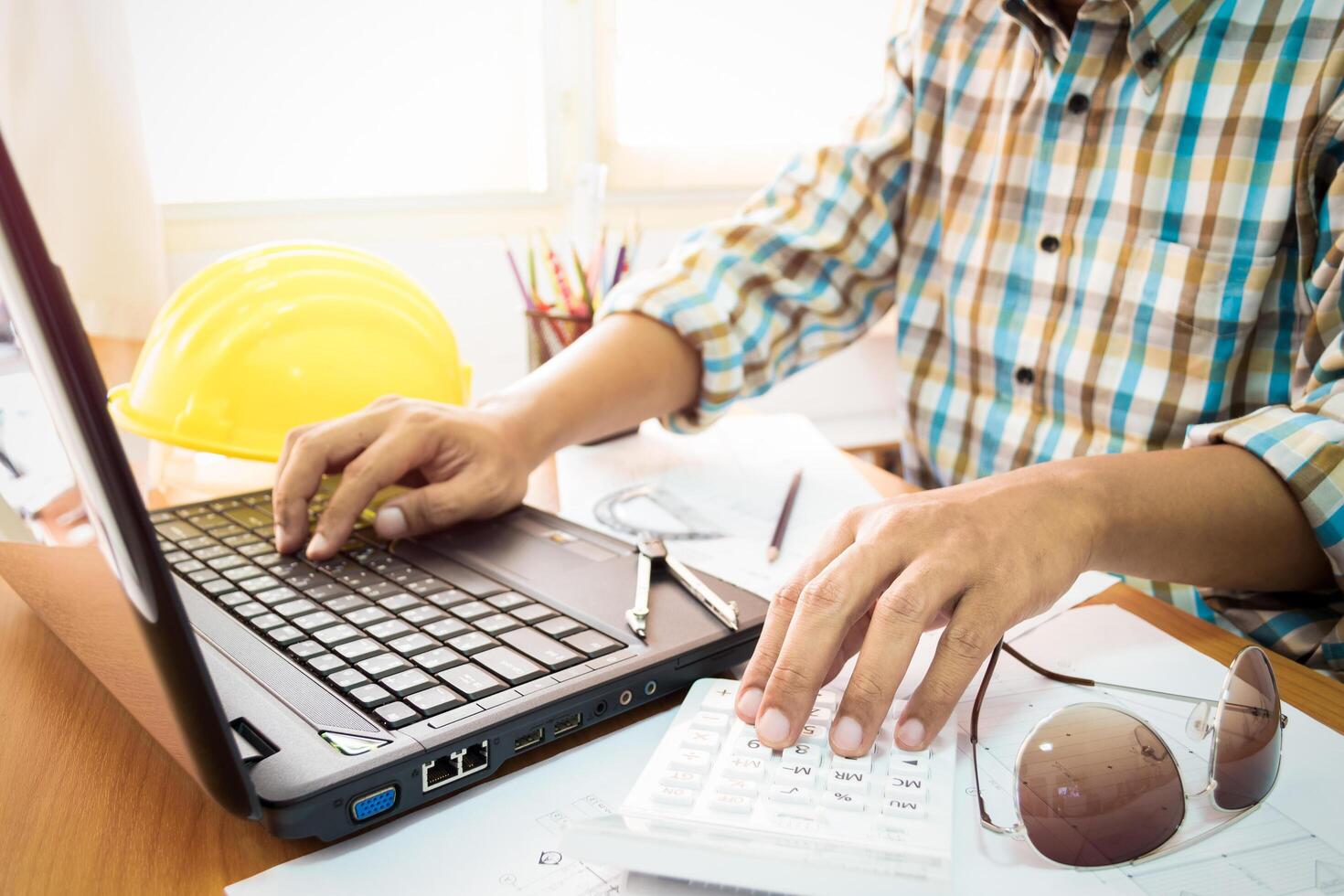 A man working on a laptop computer with a calculator photo