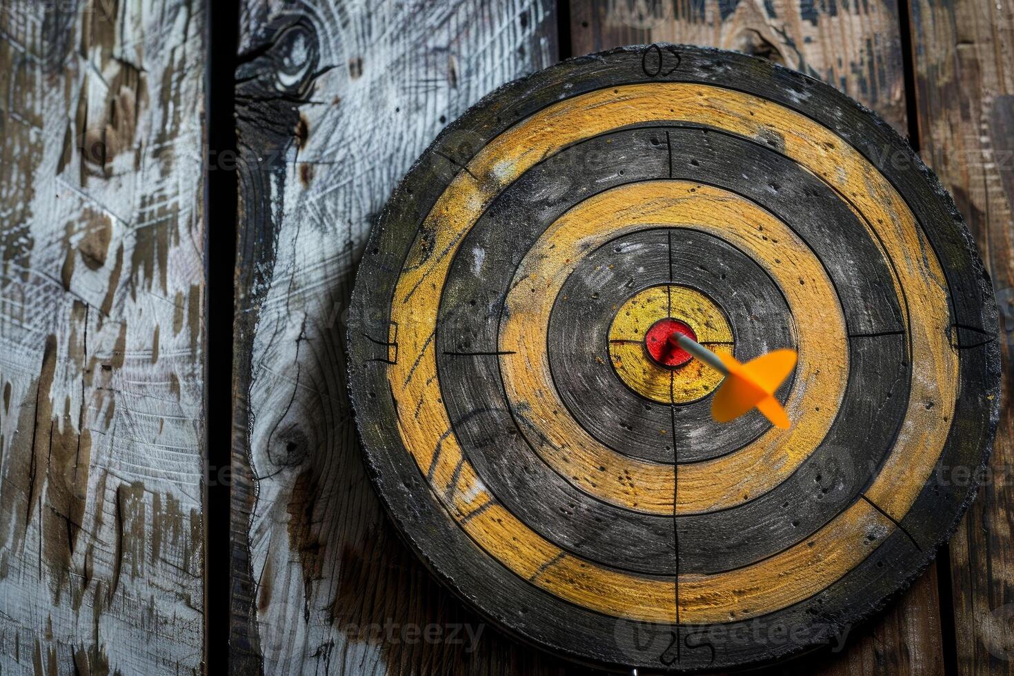 Orange dart hitting the center of an old target on a wooden background photo