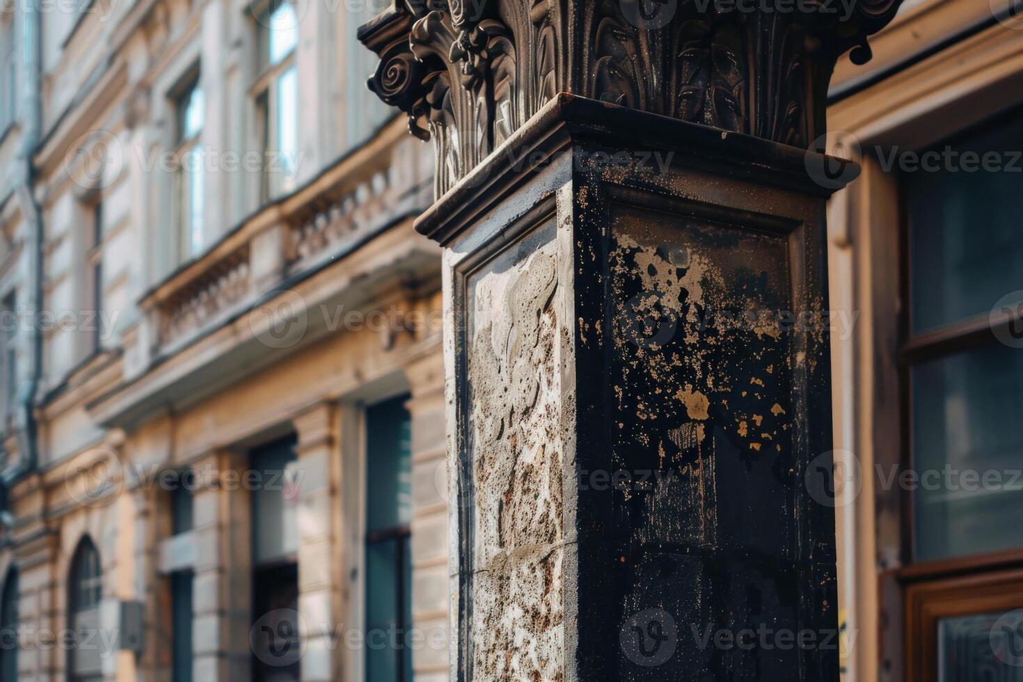 Old weathered black stone column standing in front of building photo