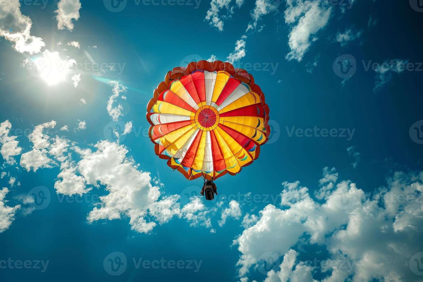 Colorful hot air balloon flying high in blue sky with white clouds and bright sun photo