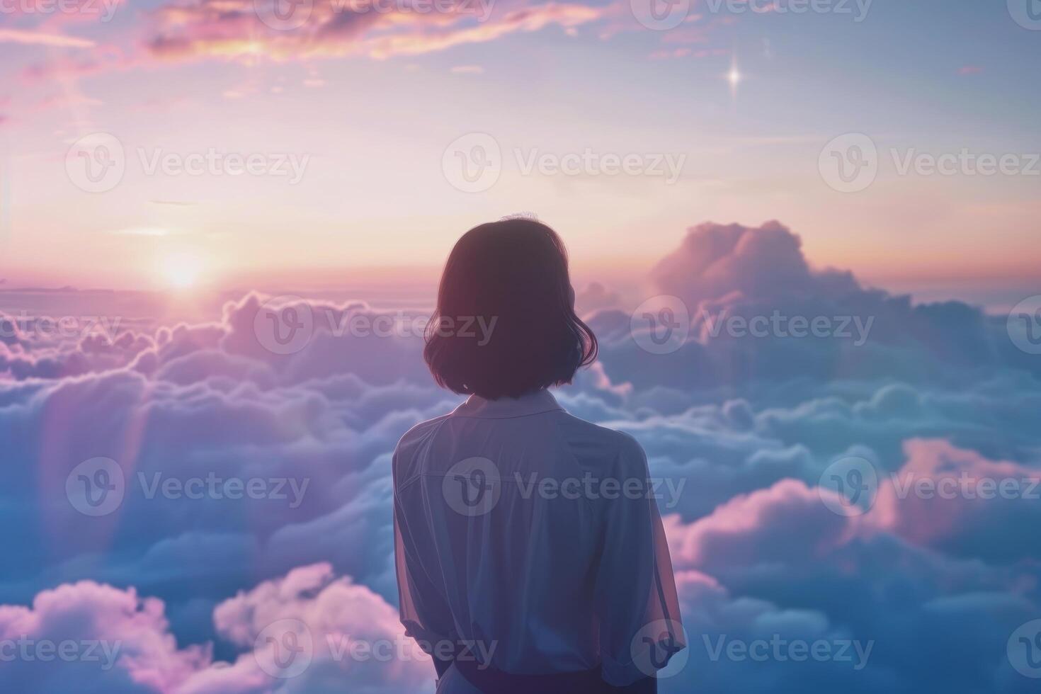 Woman standing above clouds watching beautiful sunset over horizon photo