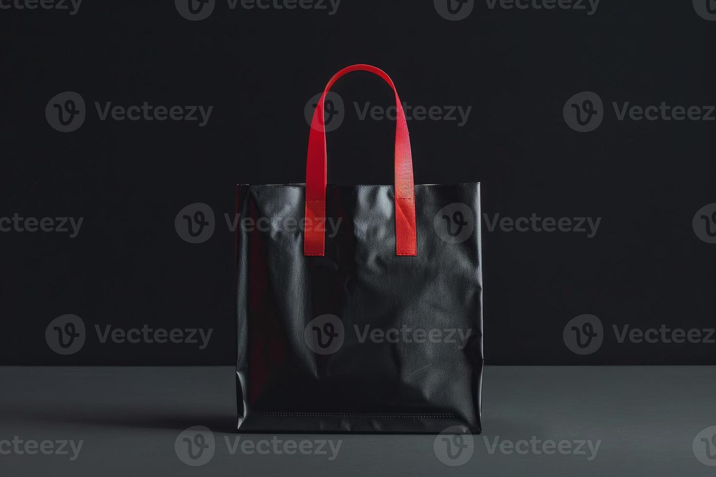 Black shopping bag standing on dark grey surface with black background photo