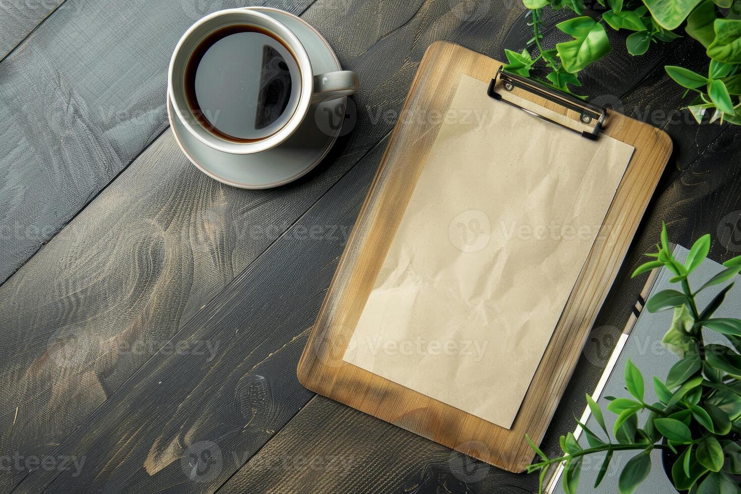 Blank clipboard lying on wooden desk with a cup of coffee and plants photo