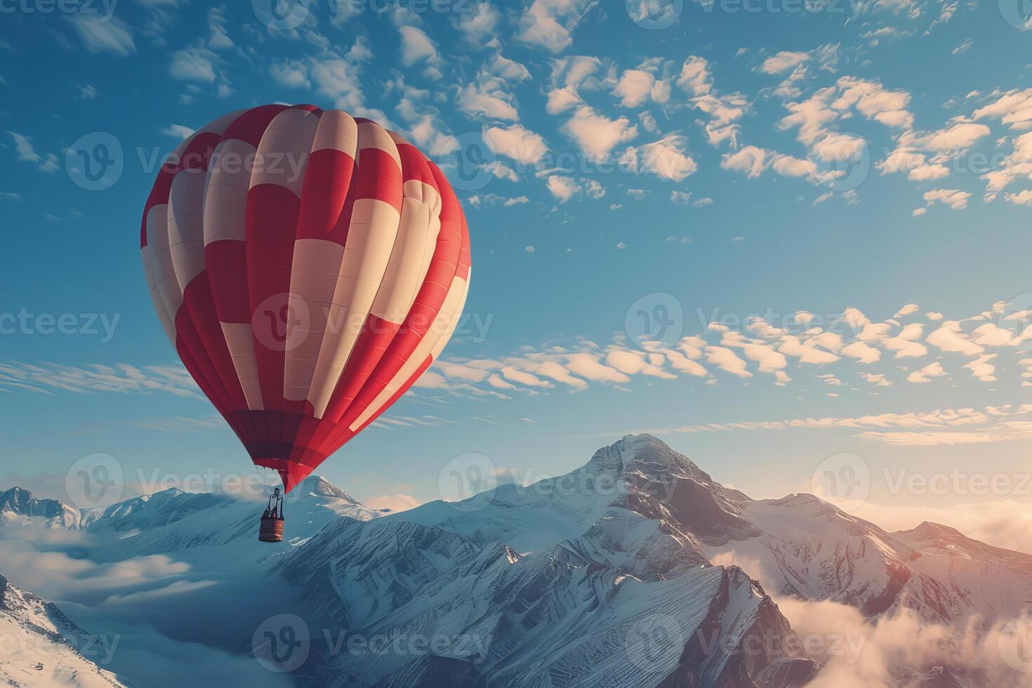 Red hot air balloon flying over snow covered mountain peaks photo