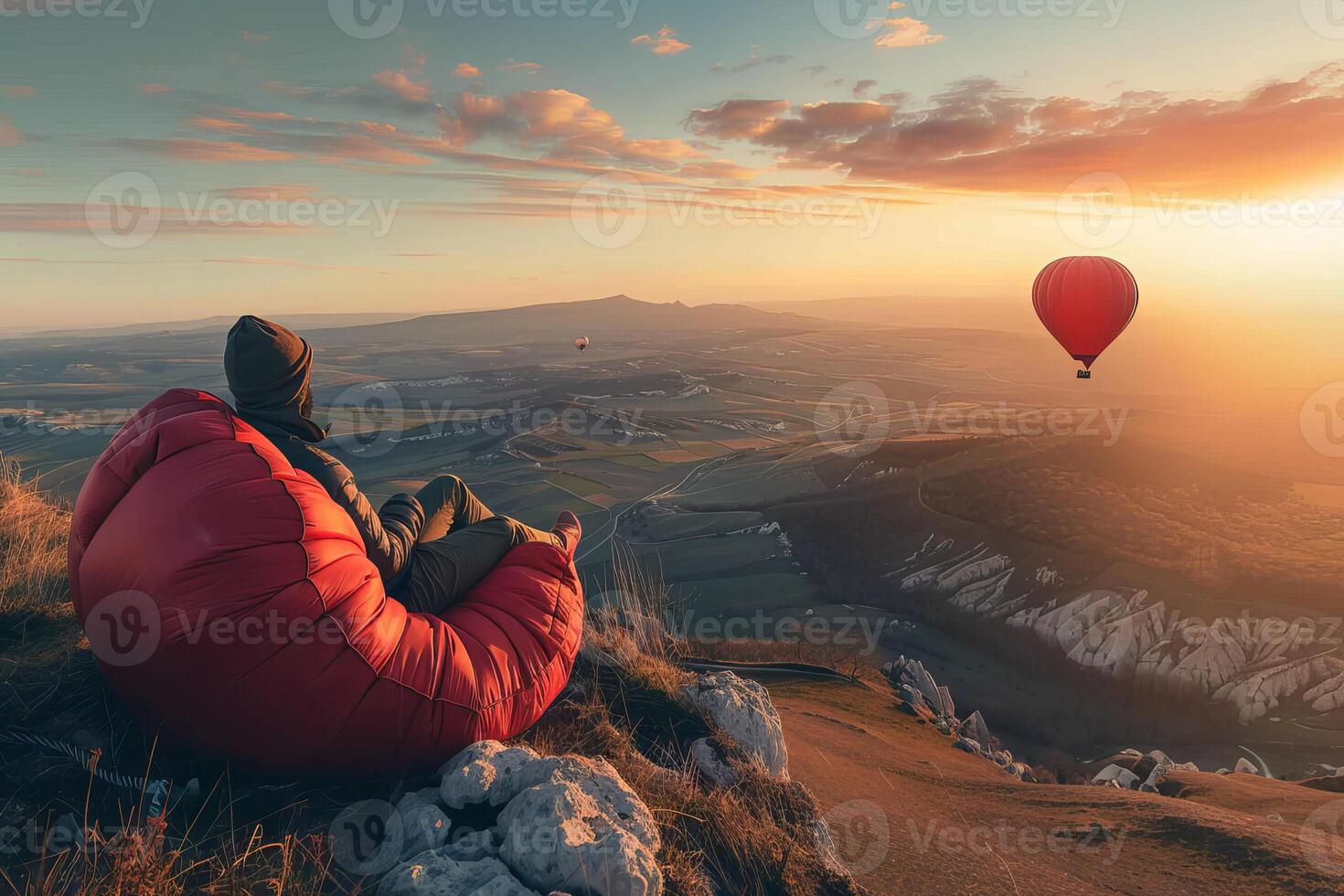 Young man relaxing in beanbag chair watching hot air balloons at sunset photo
