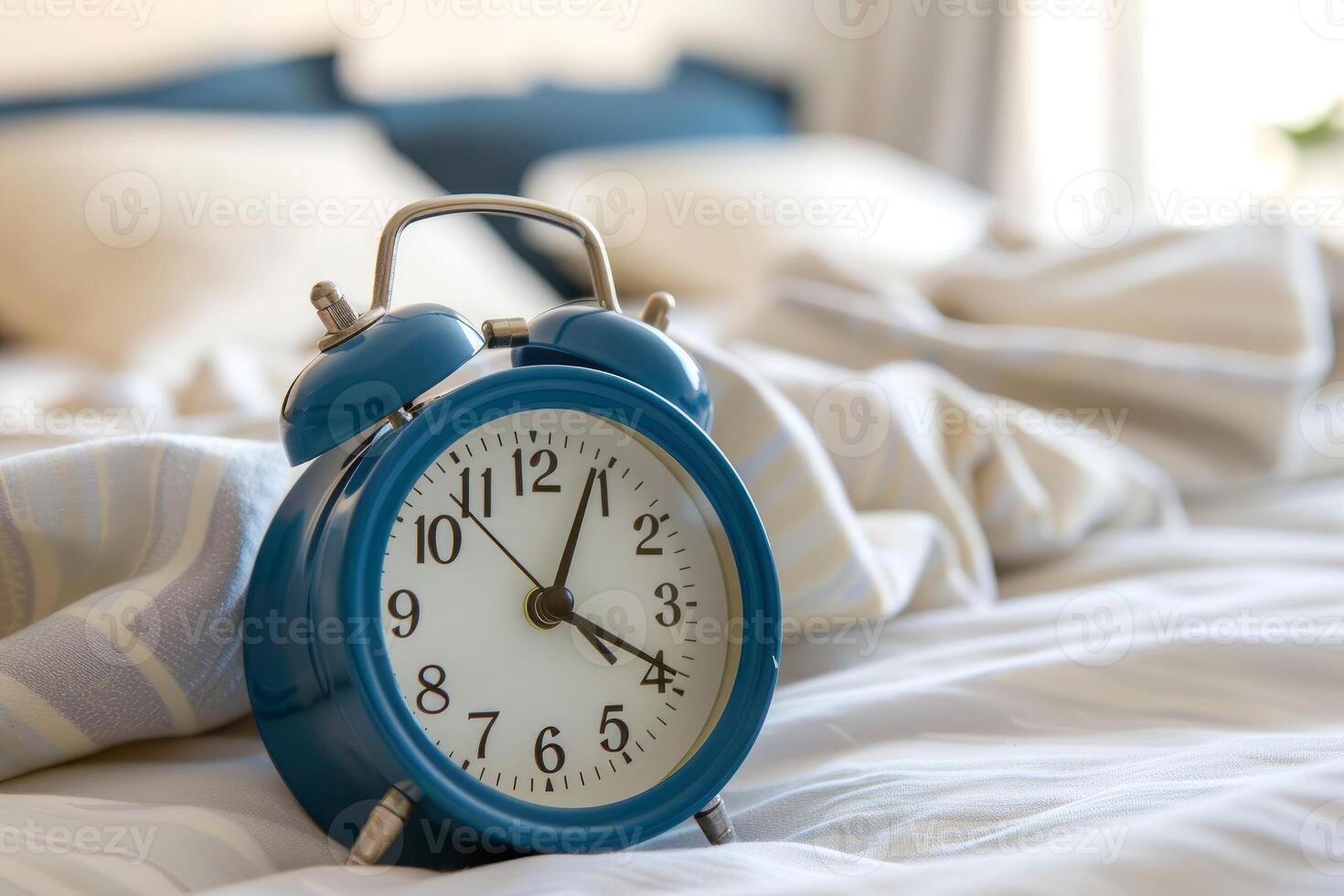 Blue alarm clock showing seven o'clock on unmade bed photo
