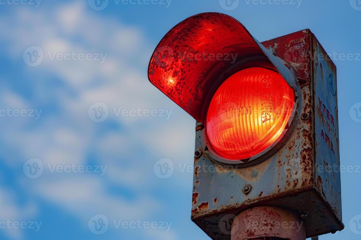 Red traffic light shining signaling stop with cloudy blue sky background photo