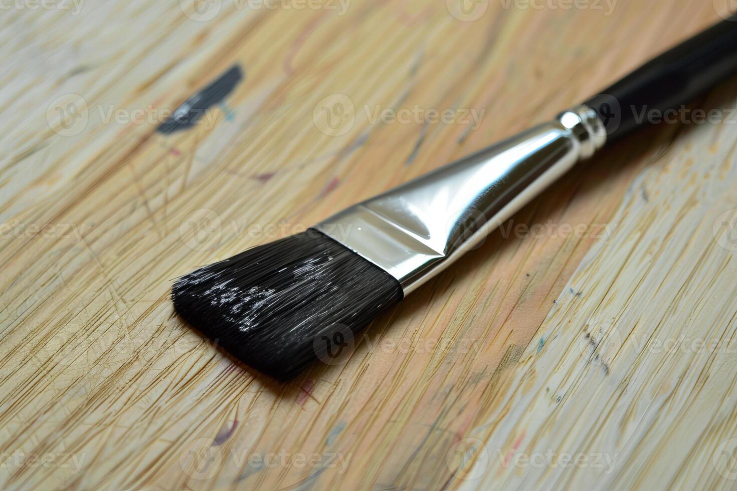 Paint brush lying on a wooden table covered with paint stains photo