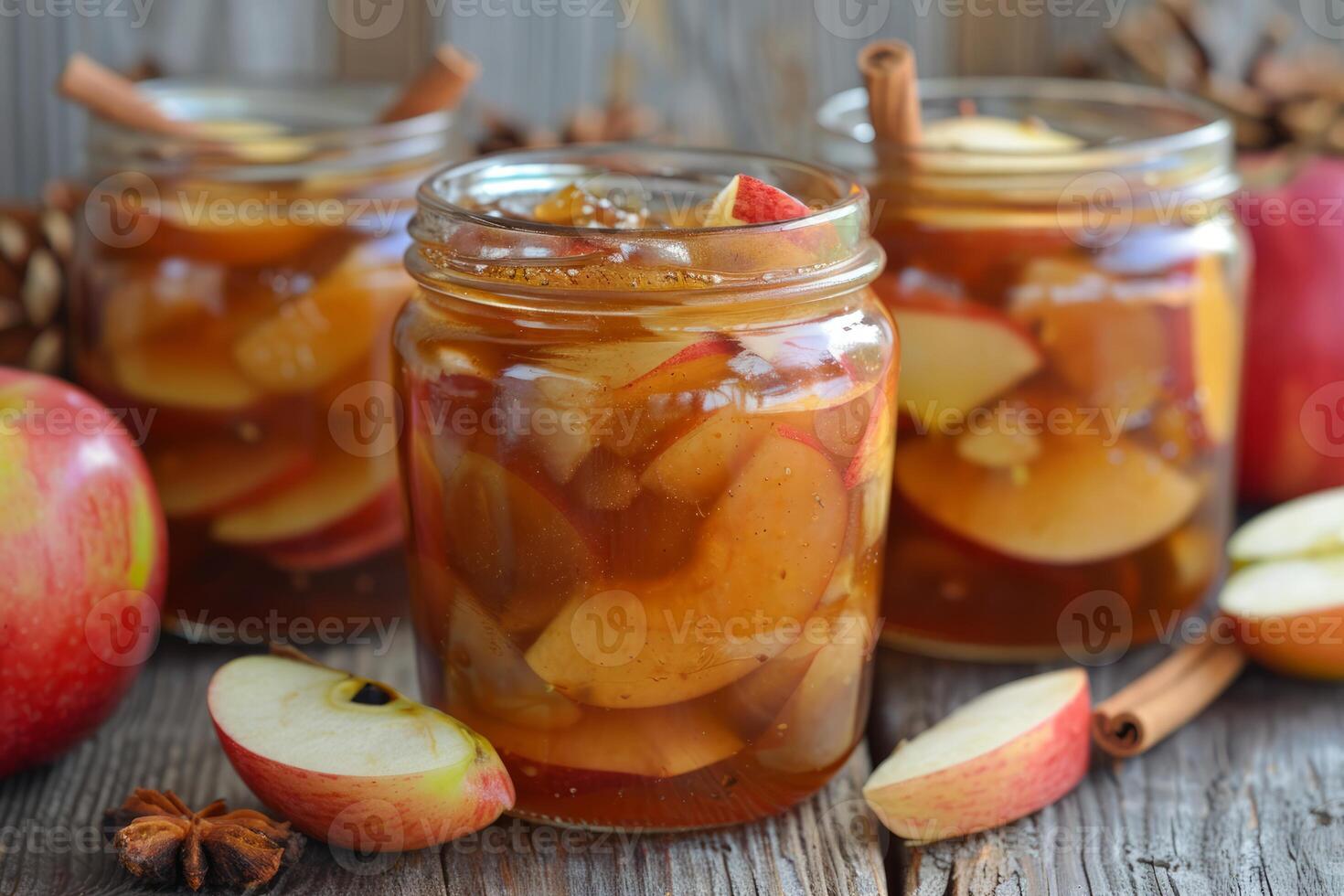 Apple compote with cinnamon sticks is standing on a wooden table photo