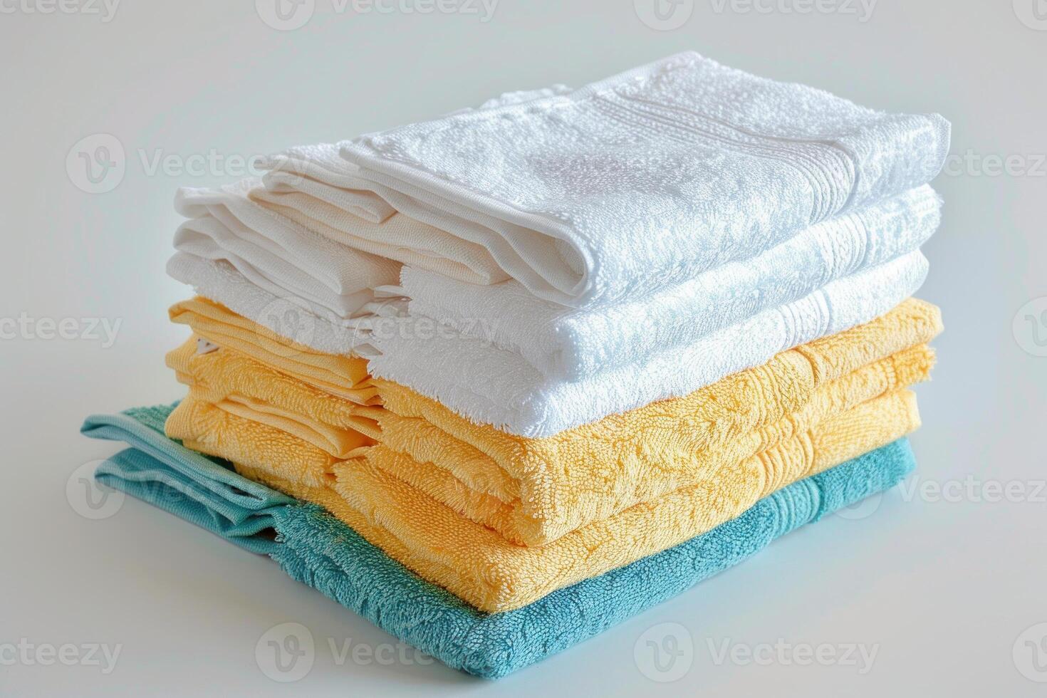Stack of clean yellow white and blue towels lying on white surface photo