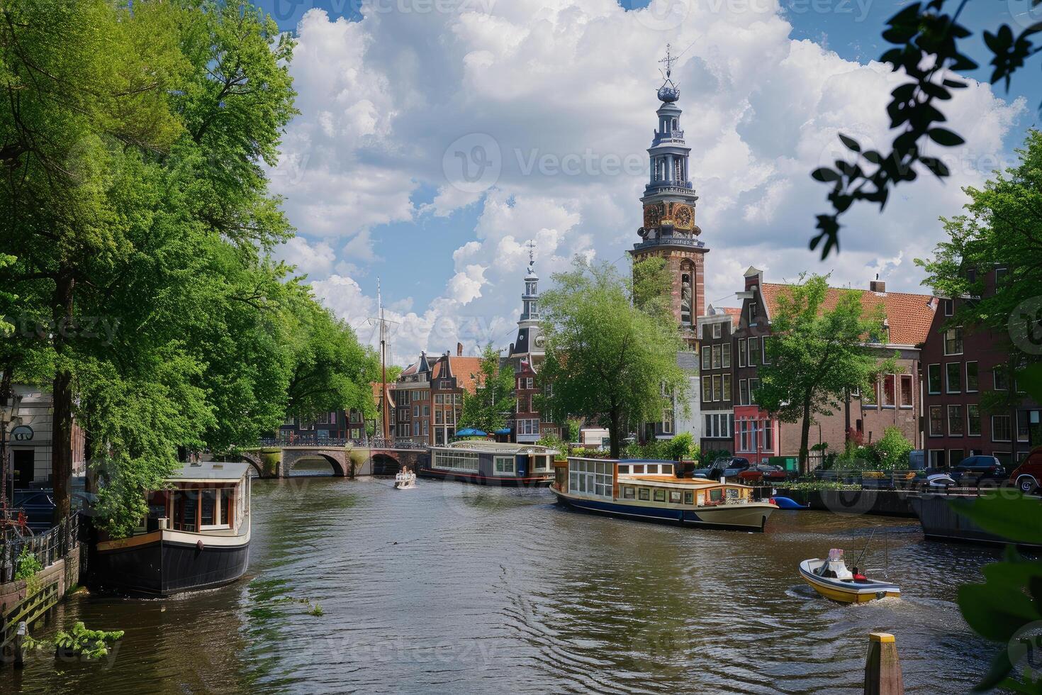 Canal boats passing under bridge in amsterdam with zuiderkerk tower in background photo
