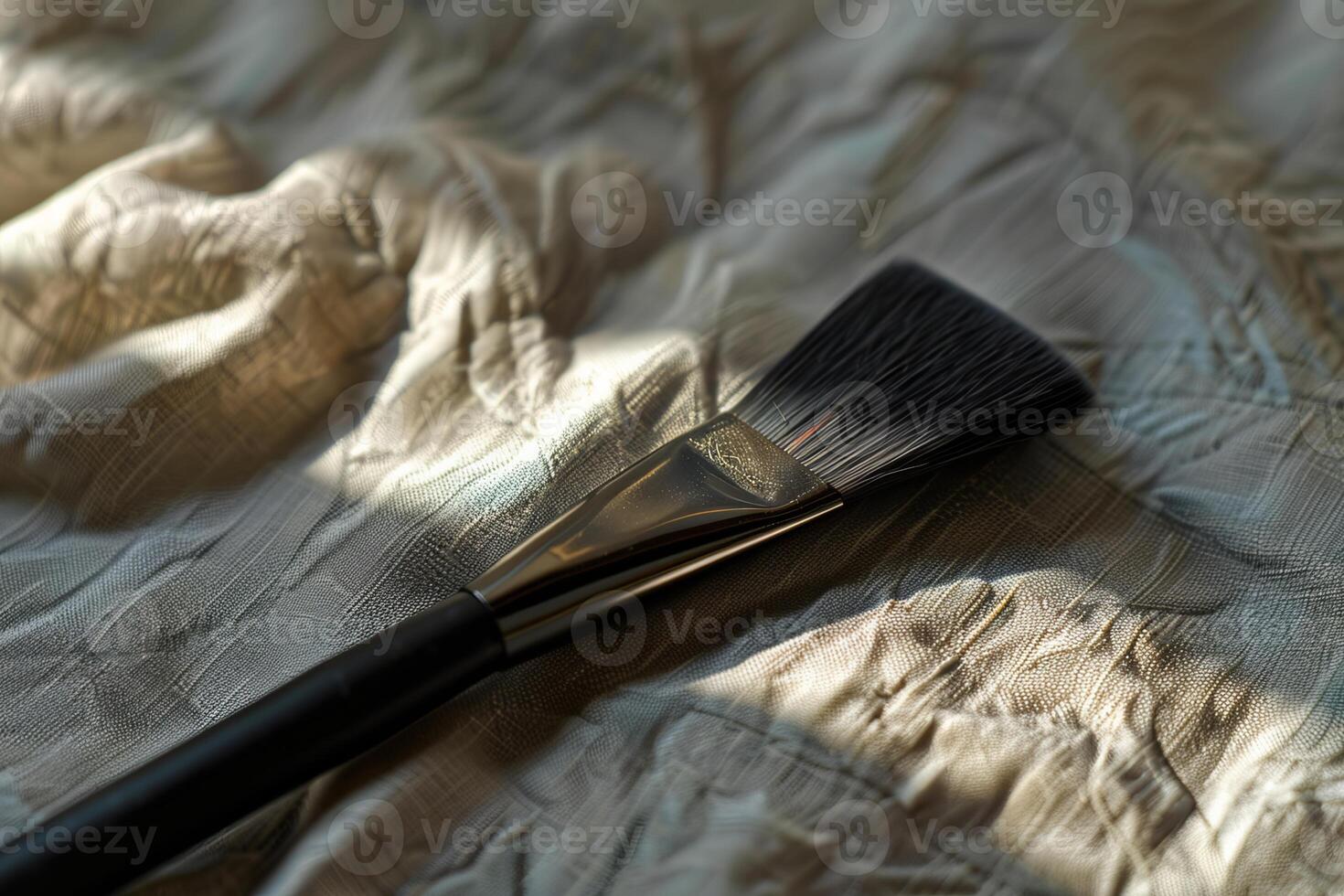 Professional makeup brush laying on white fabric in sunbeam photo