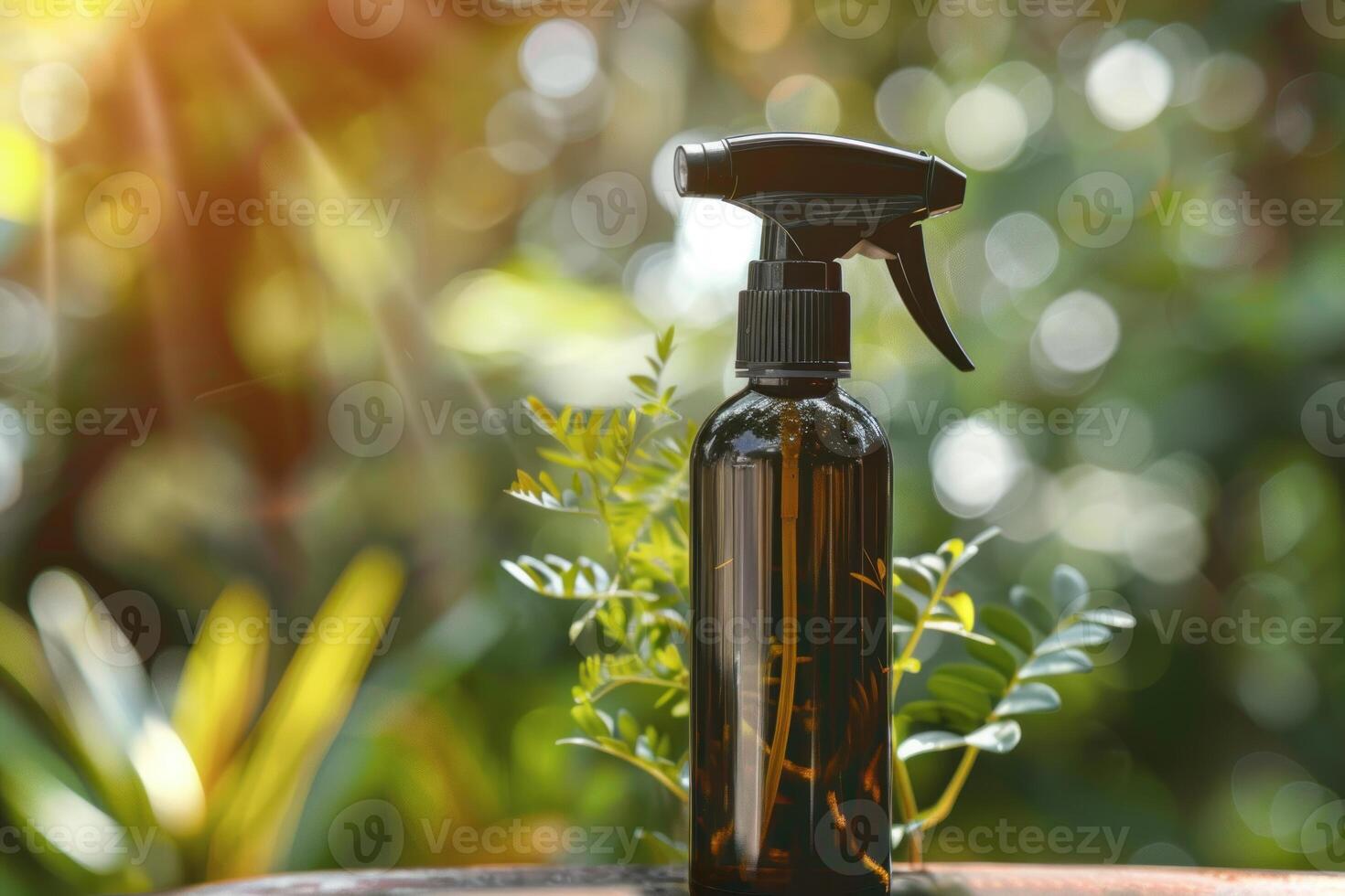 Amber glass spray bottle with black trigger sprayer sitting on a wooden surface outdoors with plants behind photo