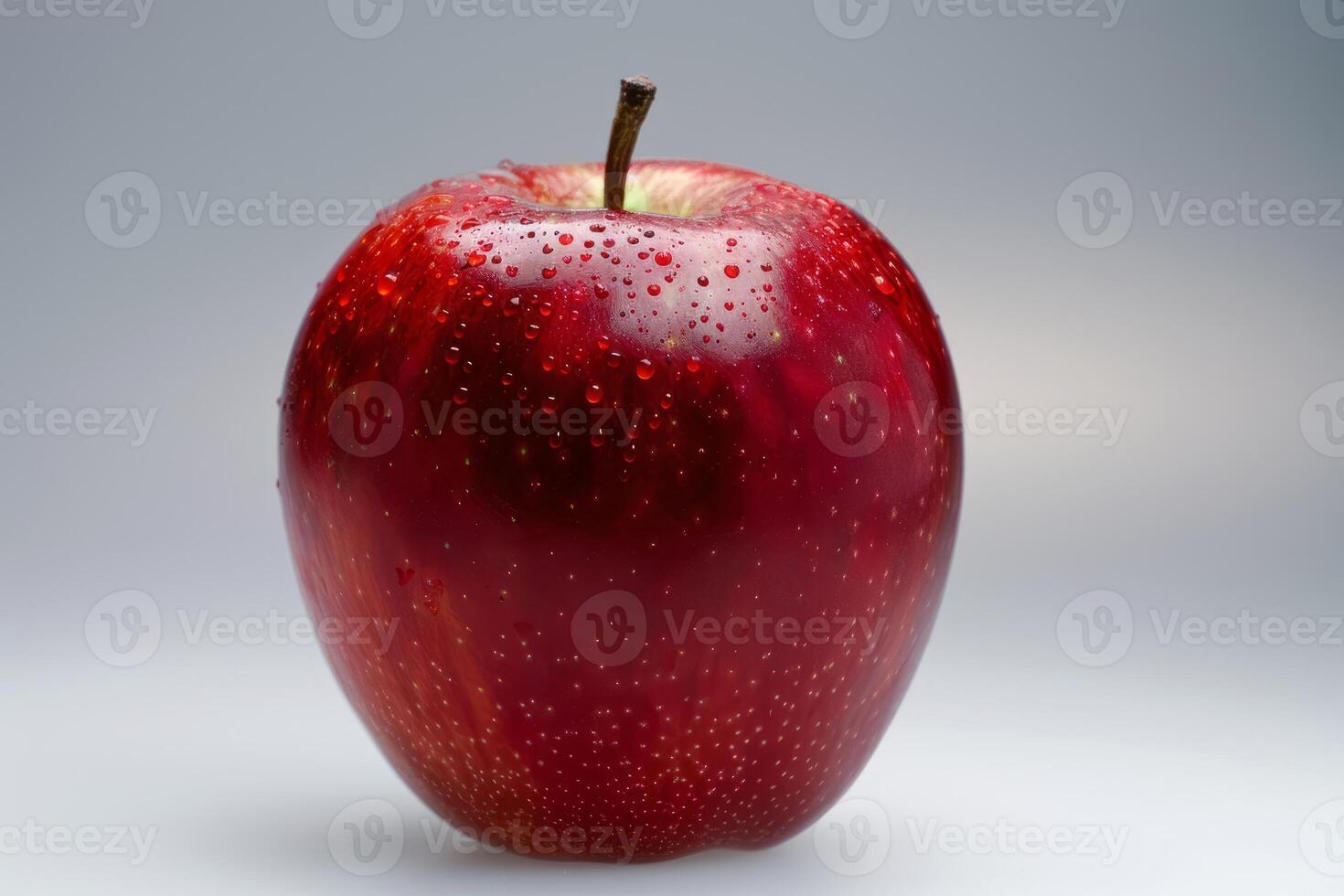 Red apple covered in water droplets is sitting on a white surface photo