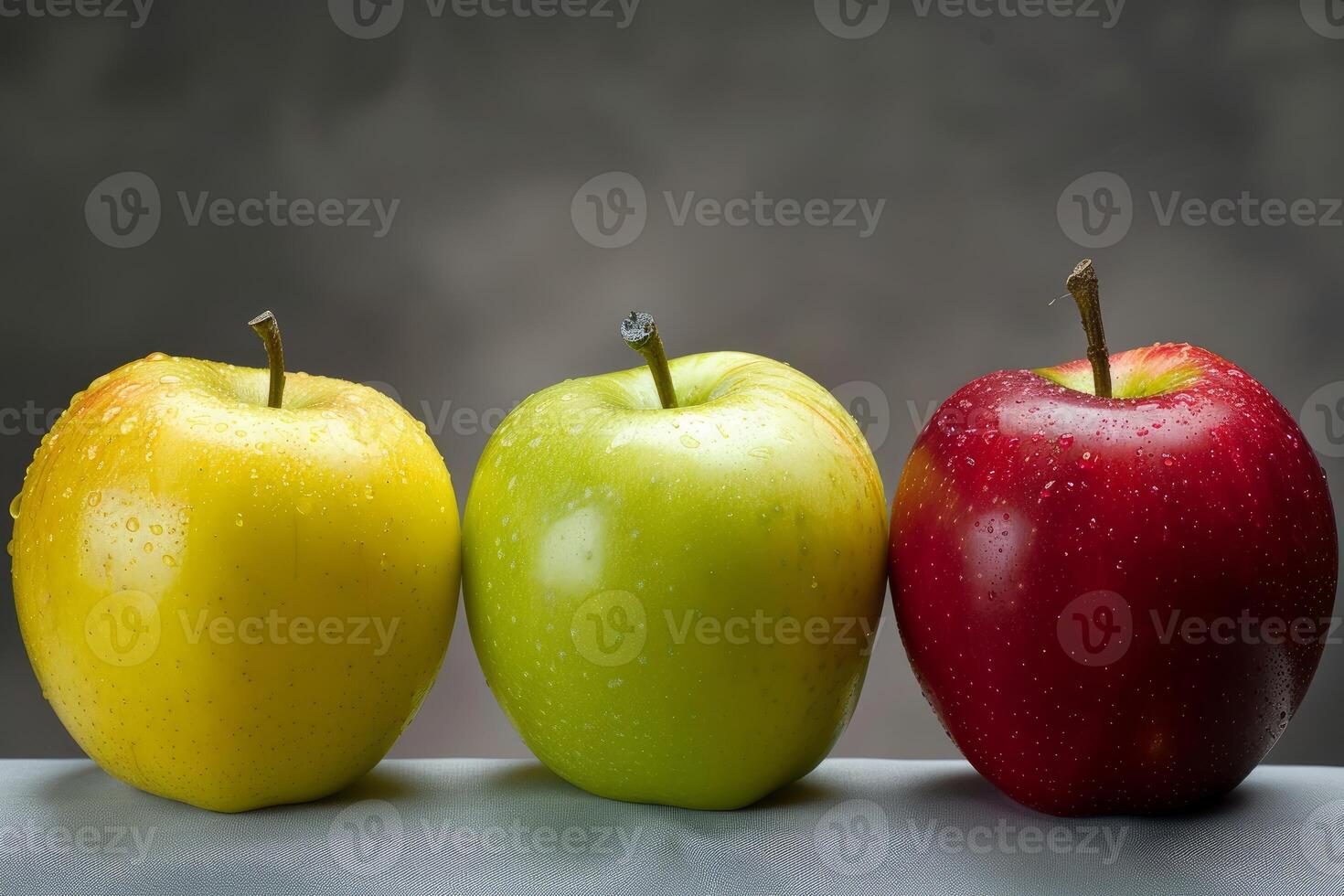 Three fresh apples standing on gray surface with dark background photo