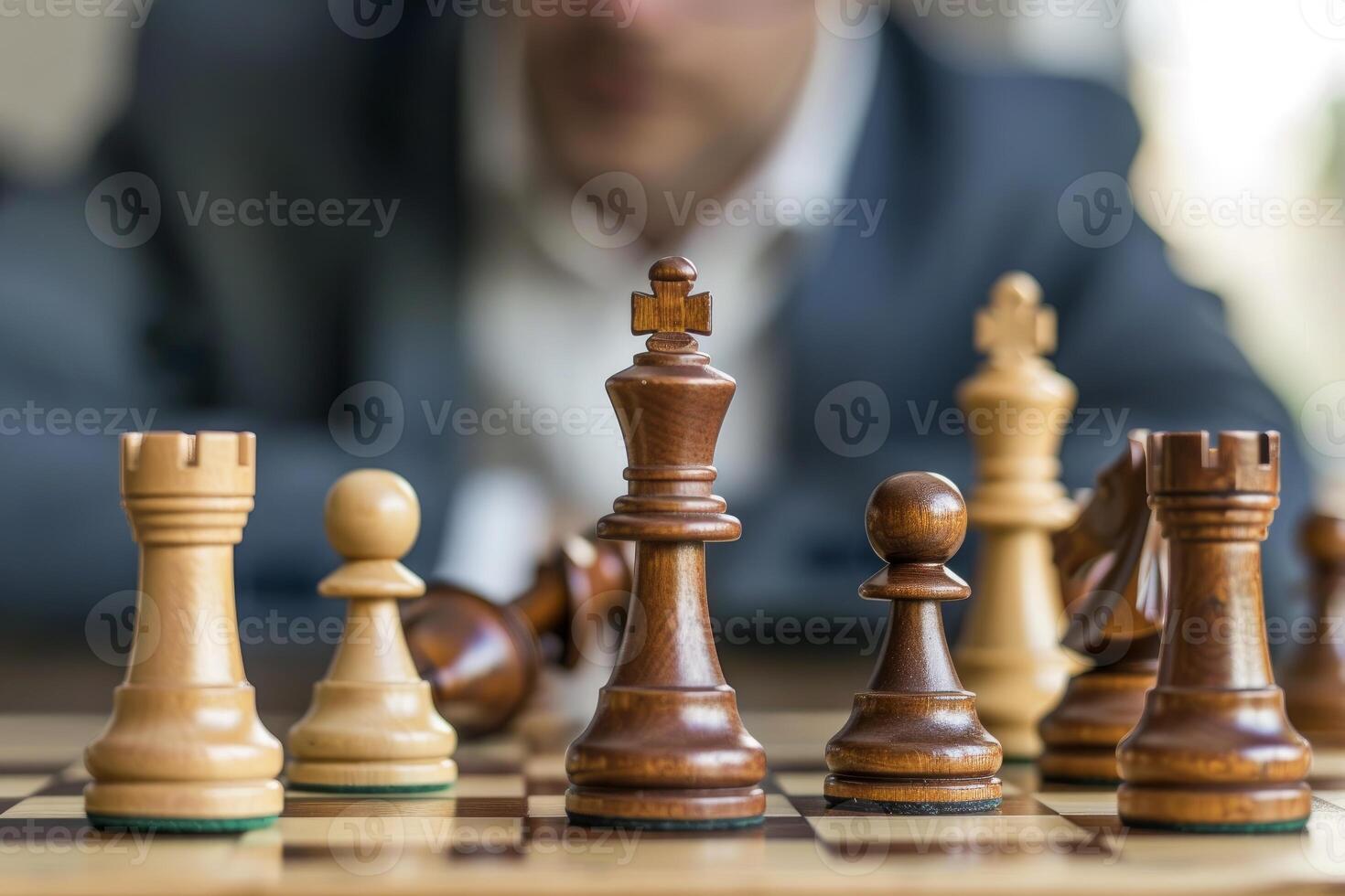 Businessman making strategic decision playing chess game with king piece in the foreground photo