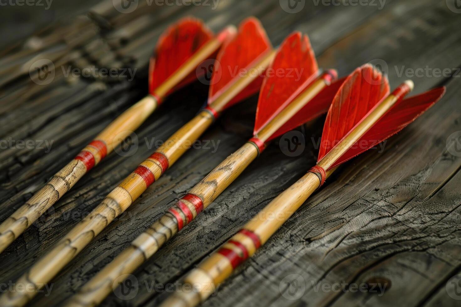 Five traditional arrows with red feathers lying on rustic wood surface photo