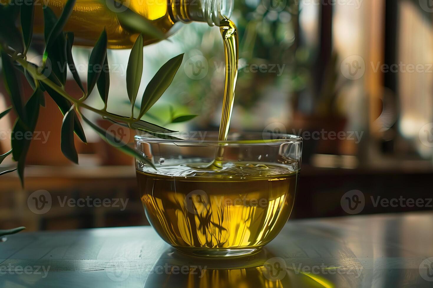 Pouring fresh olive oil into glass cup with olive branch photo