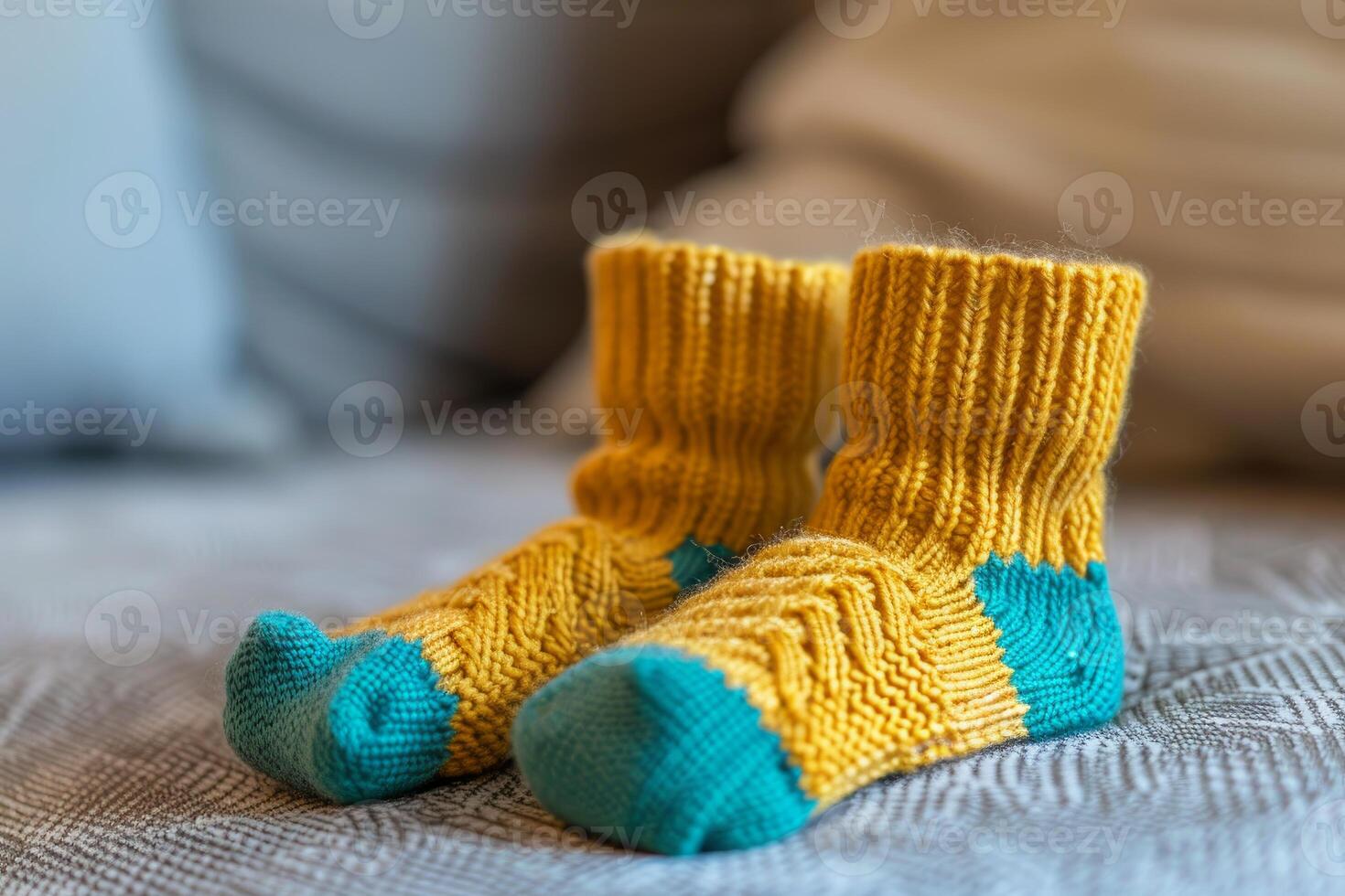 Pair of yellow and blue handmade knitted wool socks resting on a bed photo