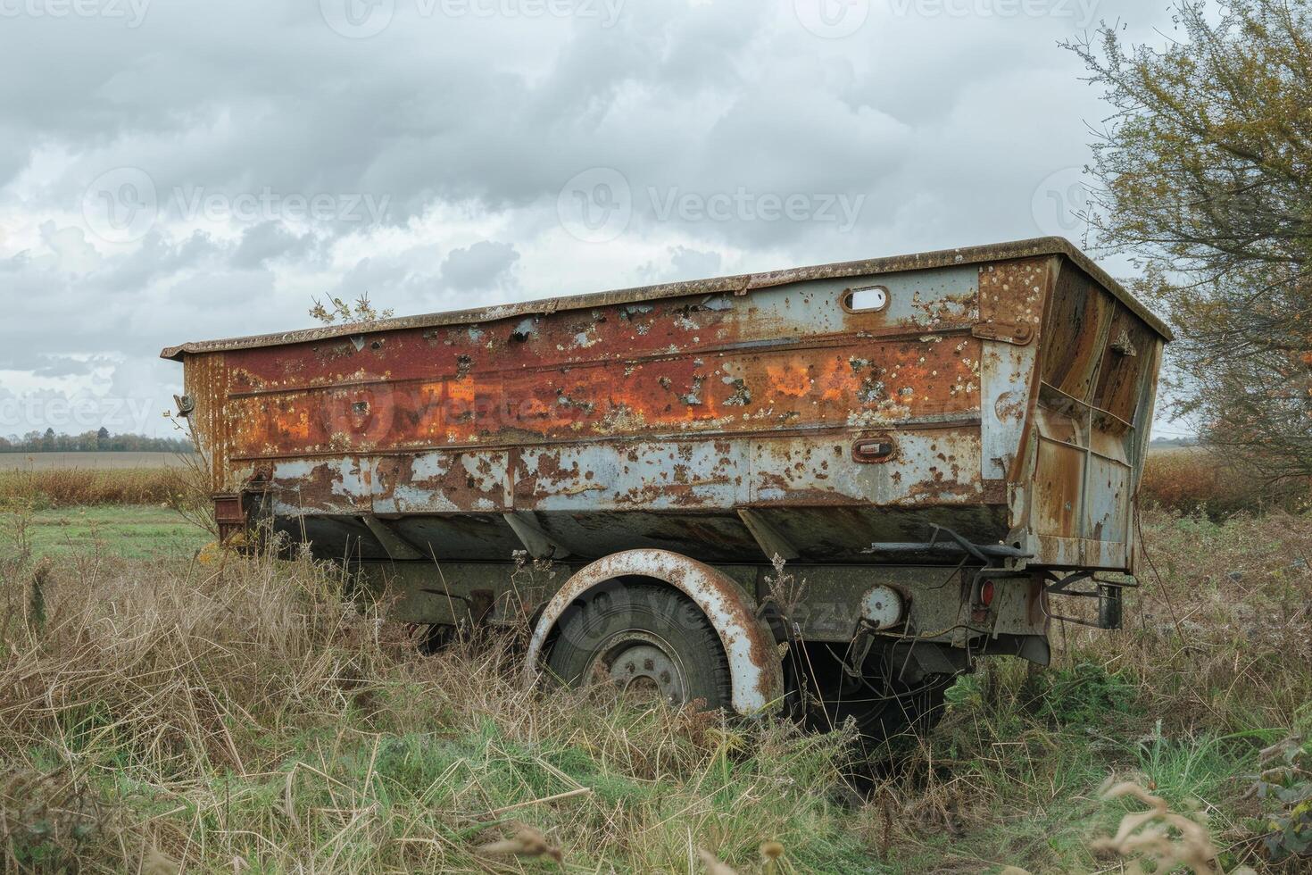 Old rusty abandoned trailer slowly decaying in a field photo