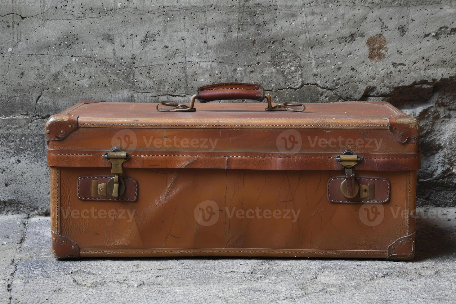 Old leather suitcase resting against a textured wall photo