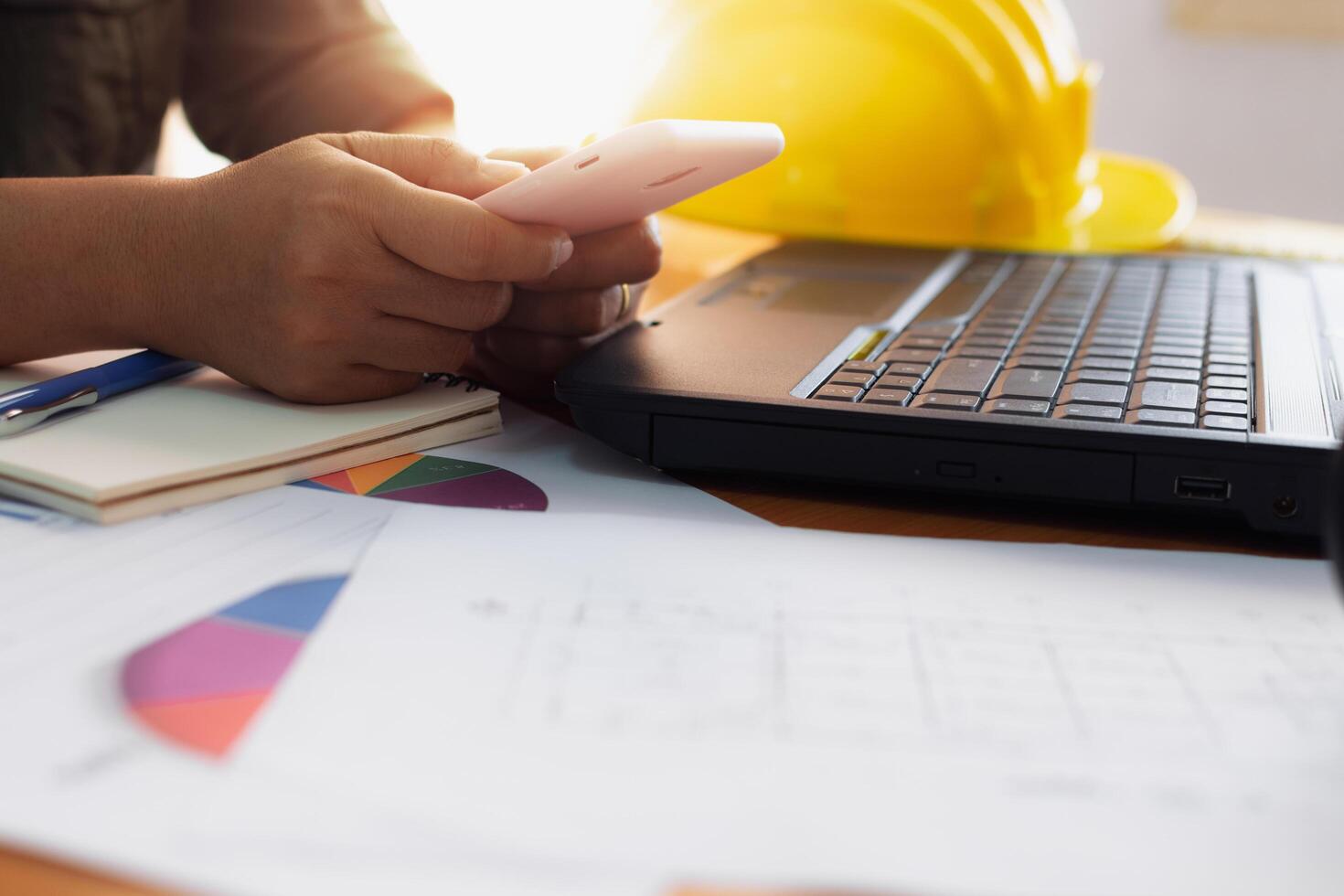 Female architect using mobilephone on working desk in office. photo