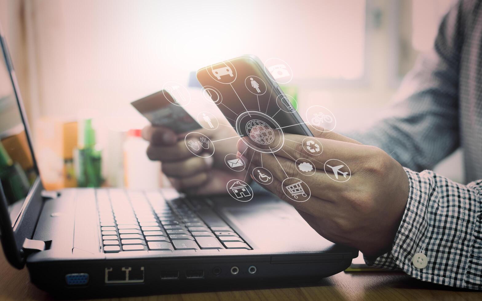 A man using a laptop and a smartphone to make a payment photo